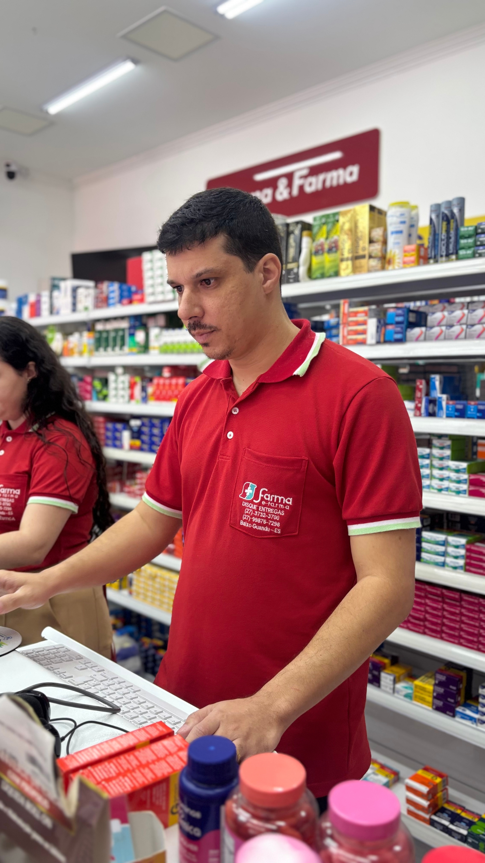 Atendente da Farma & Farma Popular realizando atendimento no balcão.